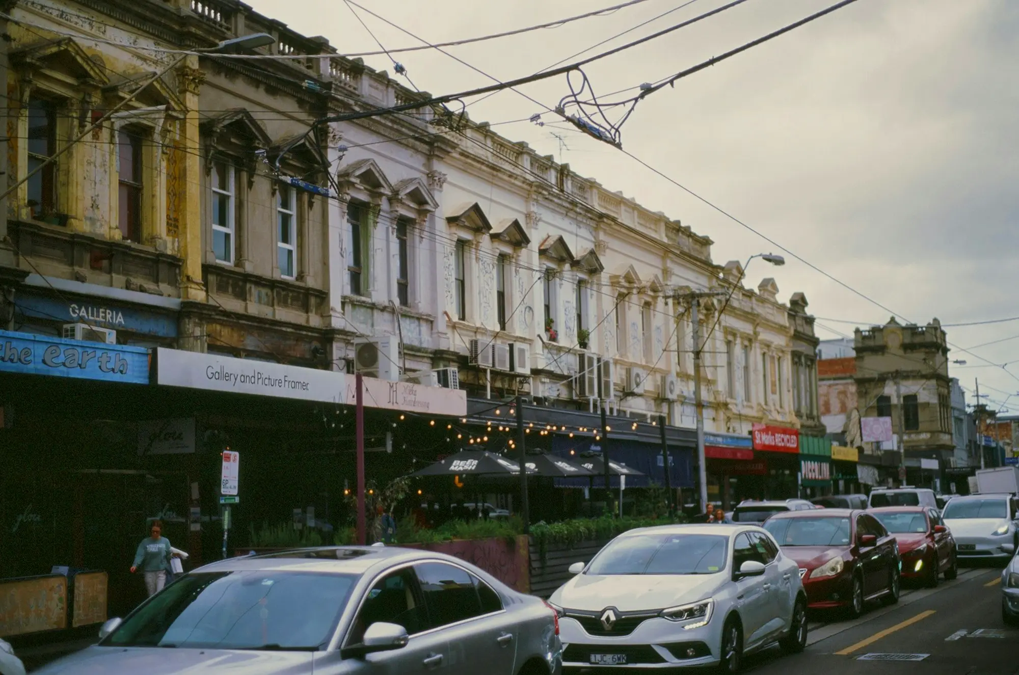 Street of heritage shopfronts and commercial buildings with parked cars