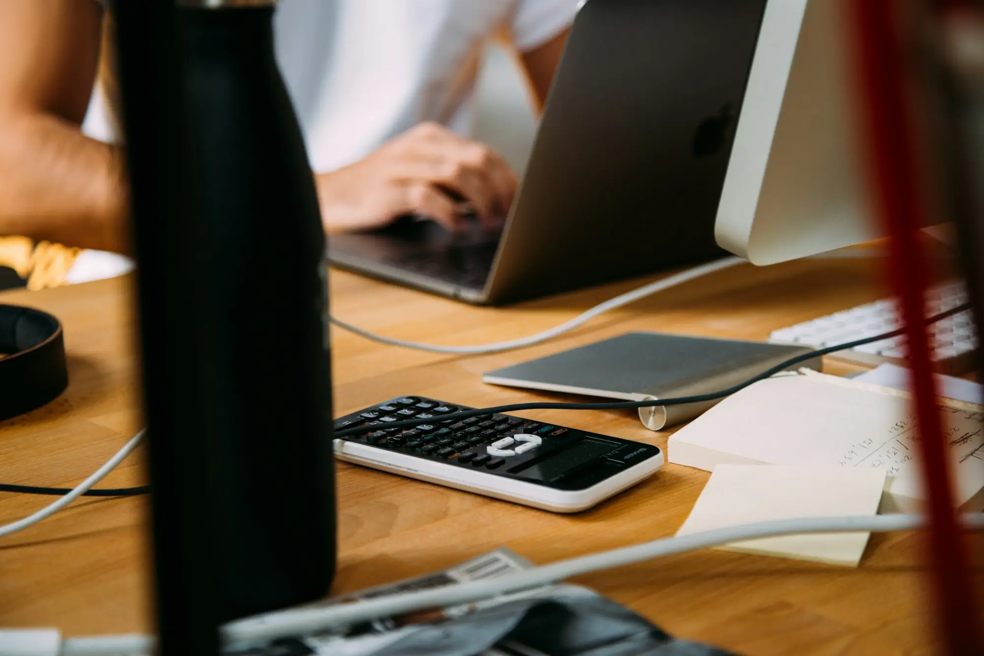 Business owner working on a laptop with a calculator and notes at tax time